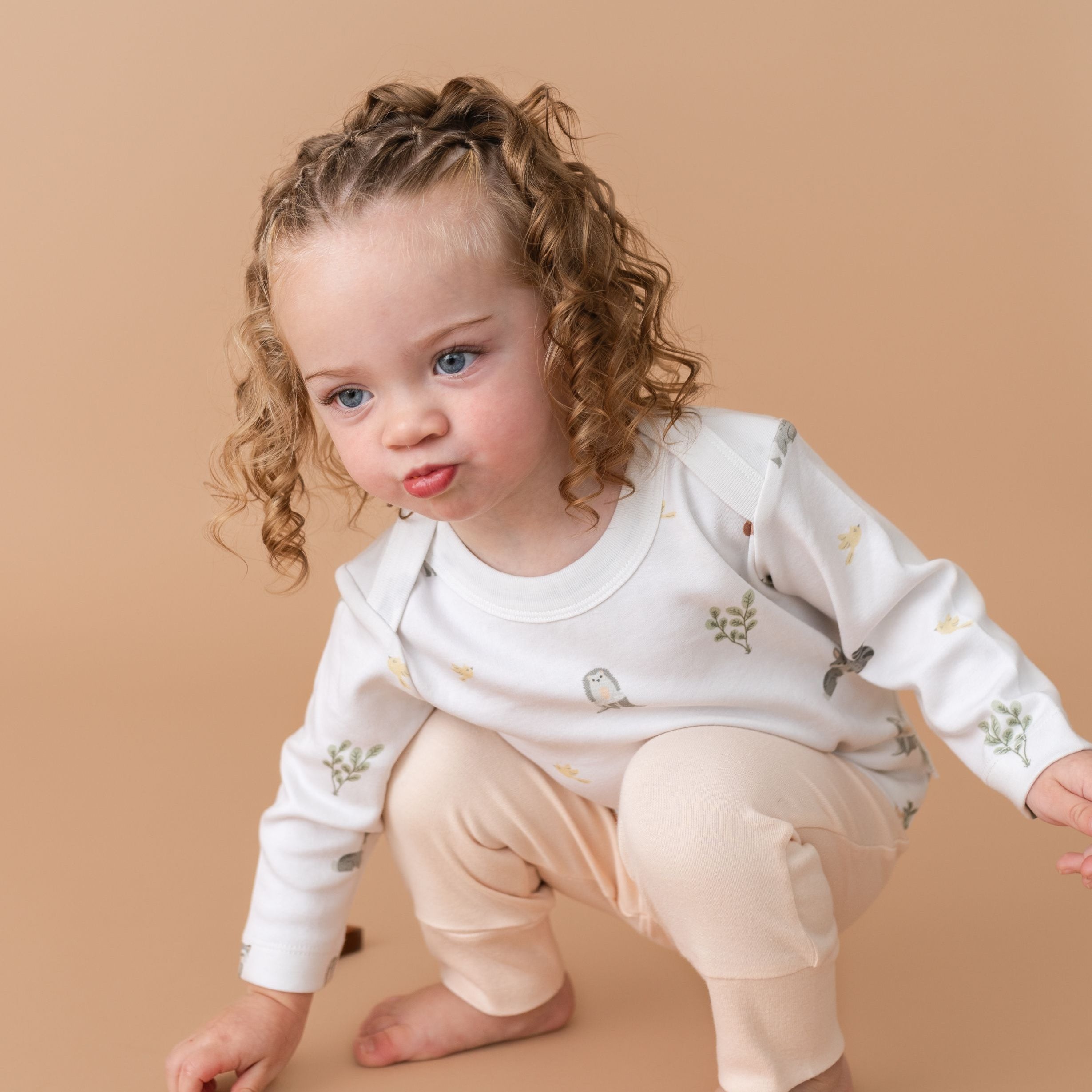 Toddler girl in Forest Friends organic cotton long sleeve shirt and rosy peach fold-over pants