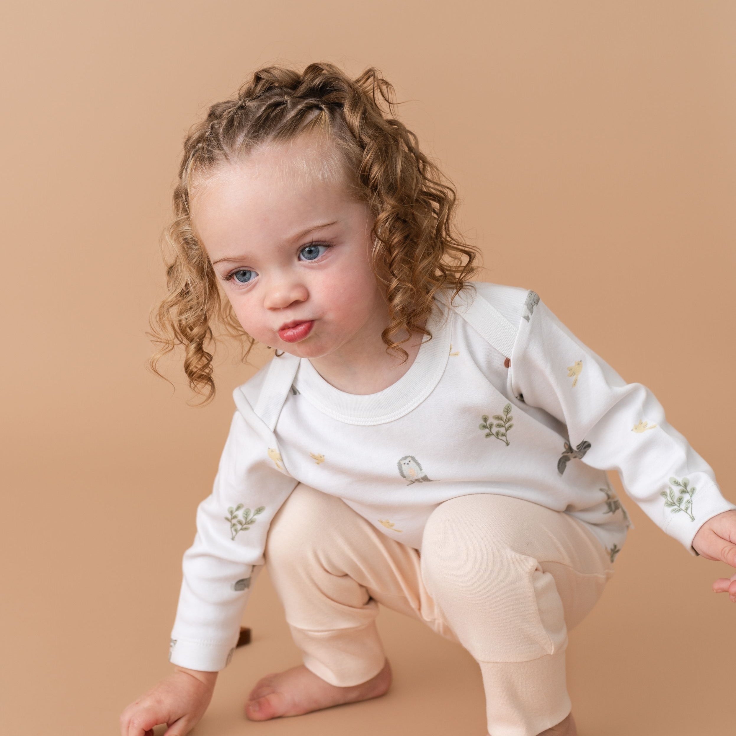 Toddler girl wearing forest friends organic cotton long sleeve shirt and rosy peach fold-over pants