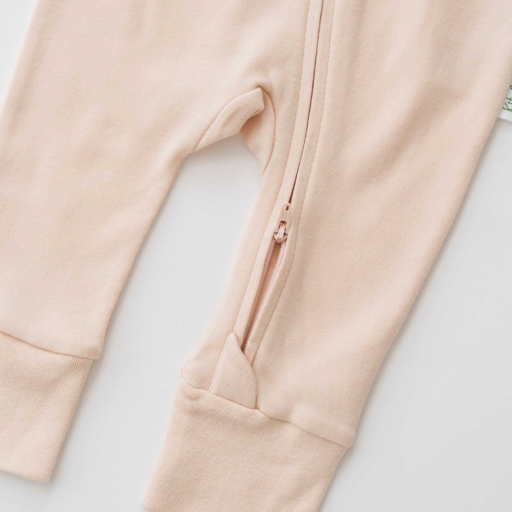 Zoomed-in view of the double zipper for easy dressing on the Rosy Peach long sleeve romper.