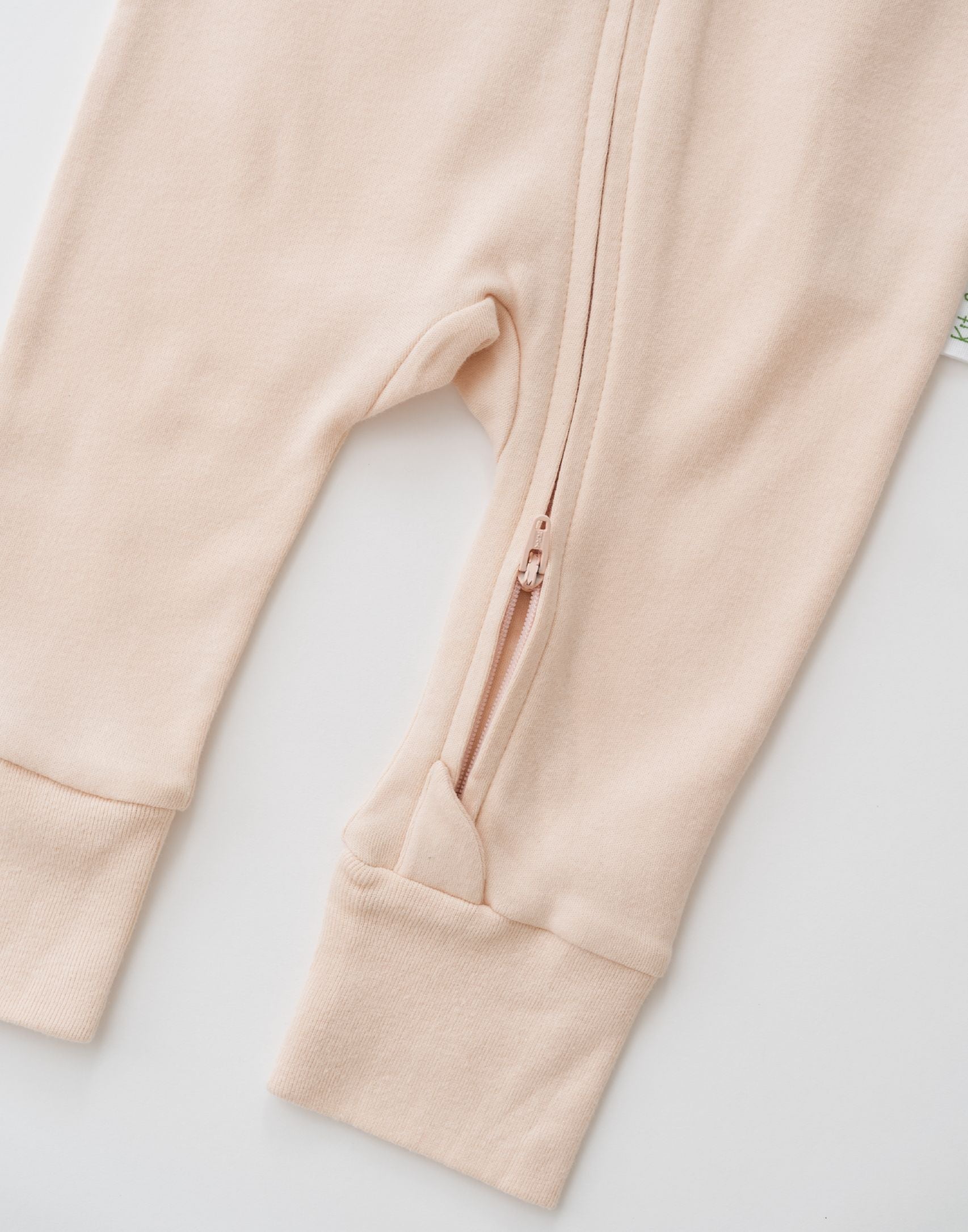 Zoomed-in view of the double zipper for easy dressing on the Rosy Peach long sleeve romper.