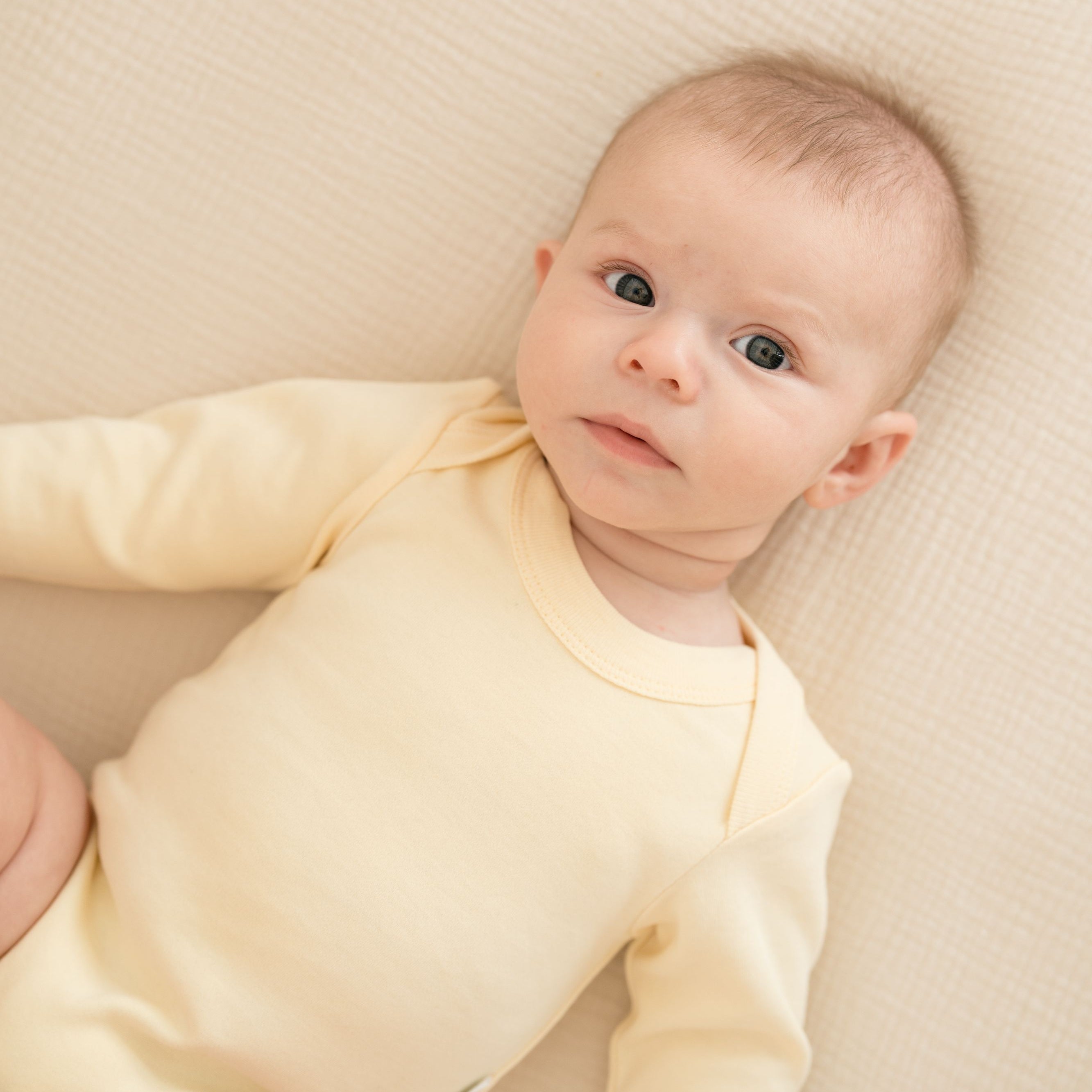 Baby wearing a Sunny Yellow organic cotton long sleeve bodysuit.
