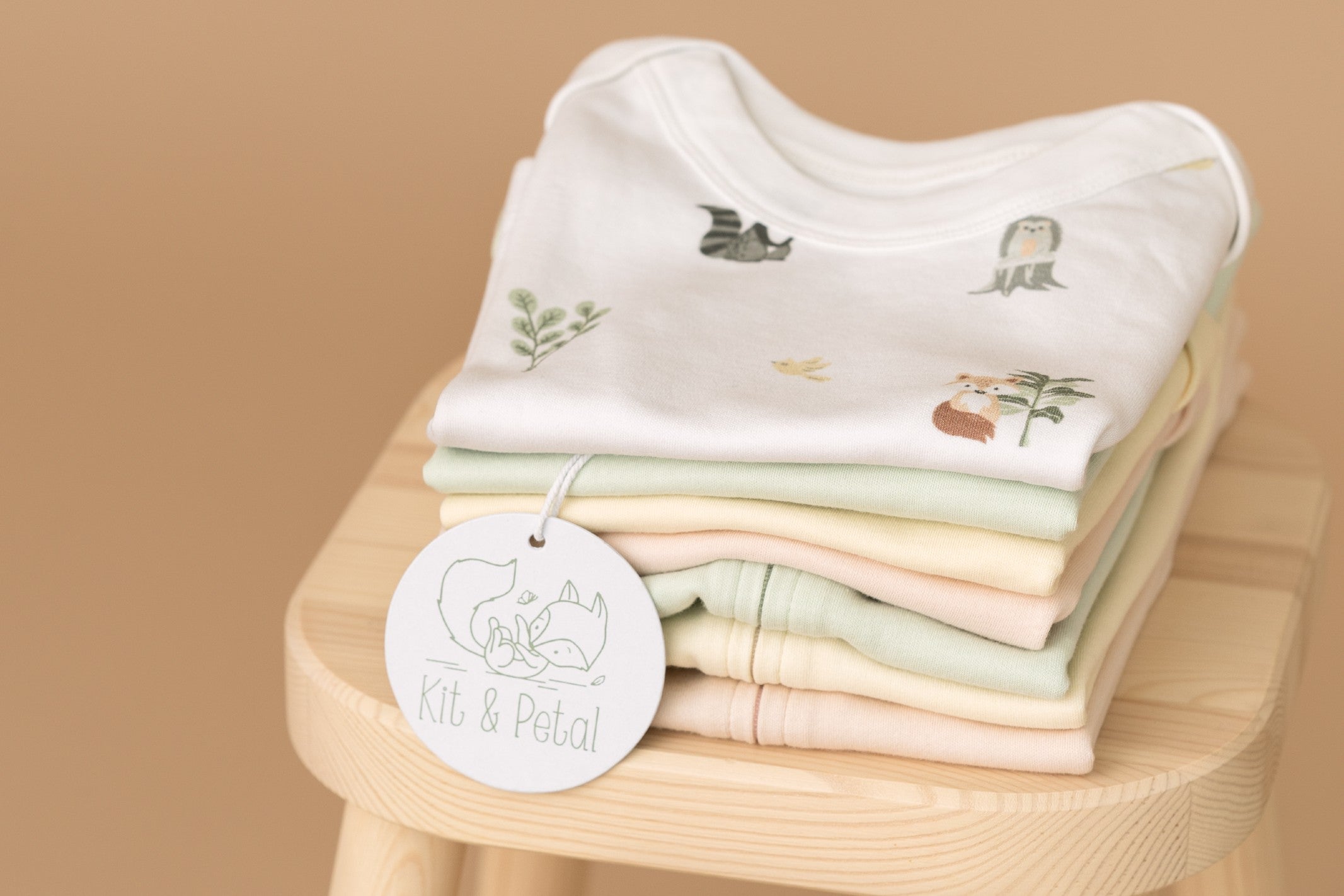 Stack of Kit & Petal clothing on a wooden chair