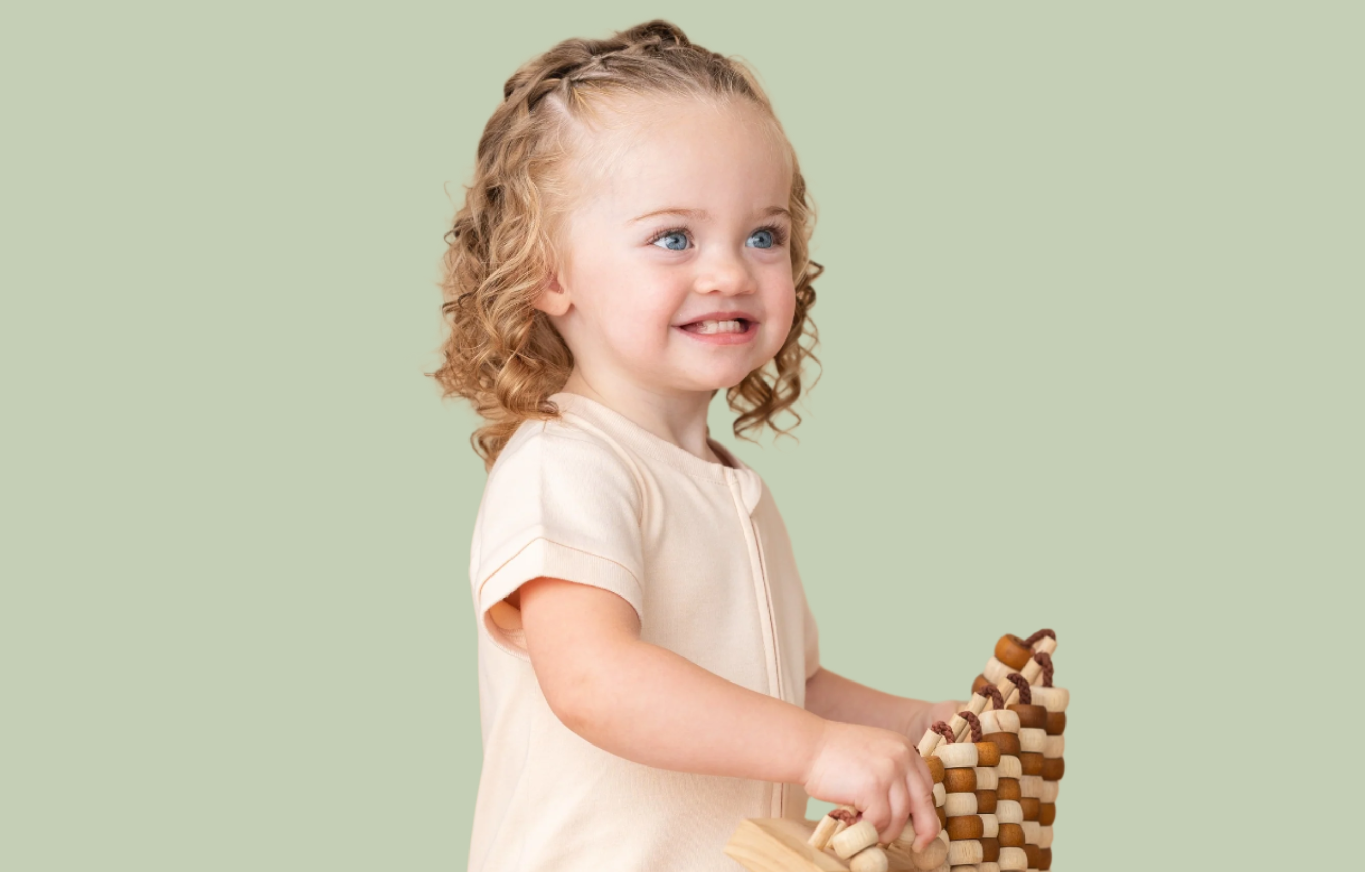 Toddler girl smiling while wearing a Rosy Peach Kit & Petal short sleeve romper.