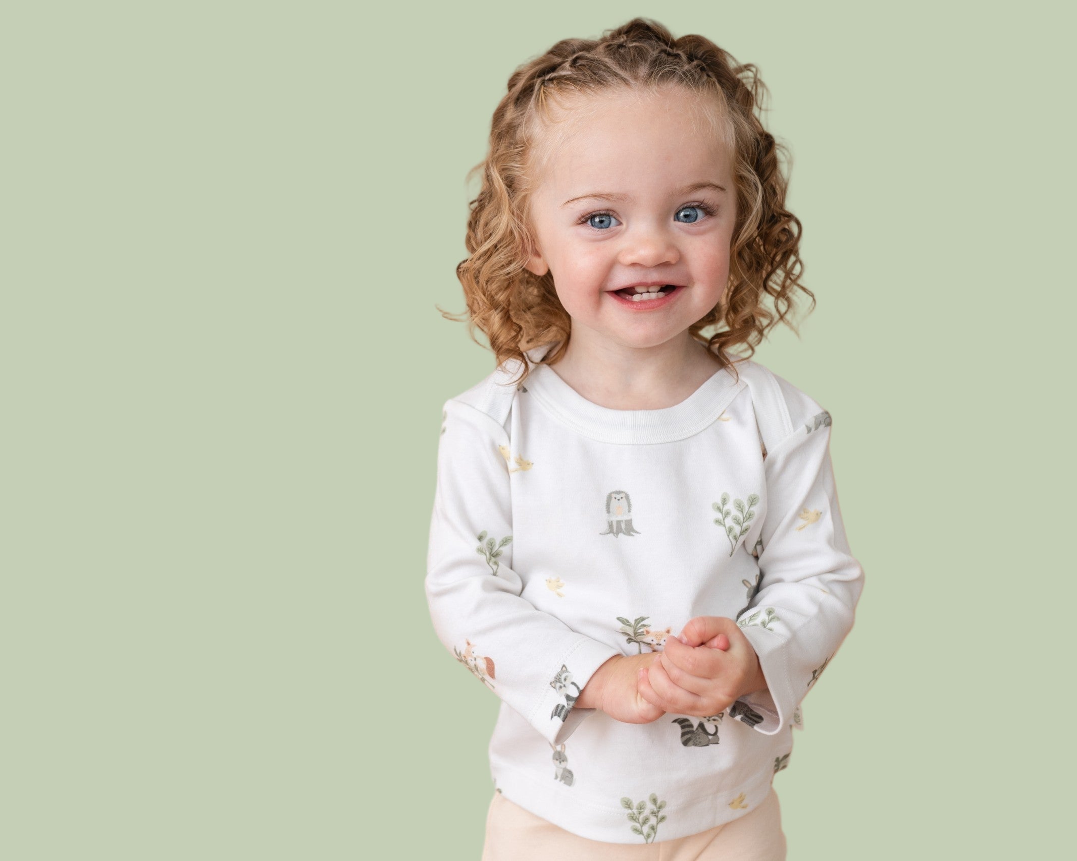 Smiling toddler girl wearing long sleeve shirt in forest friends animal print