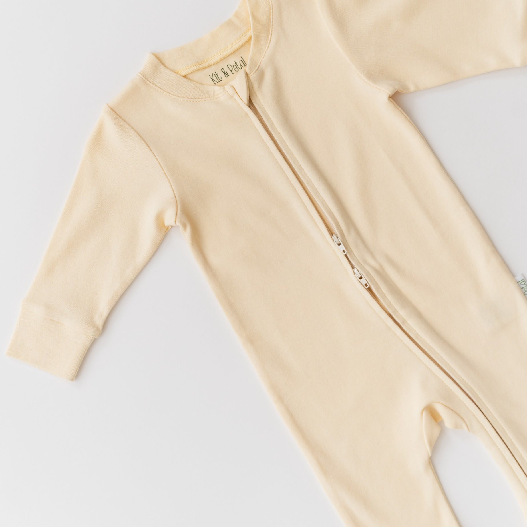 Close-up of double zipper on sunny yellow organic cotton baby long sleeve romper