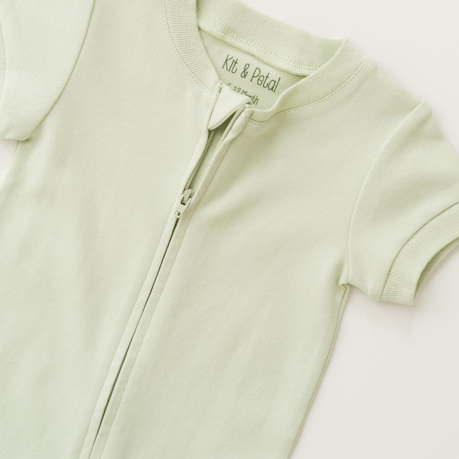 Close-up of double zipper on leafy green organic cotton baby romper