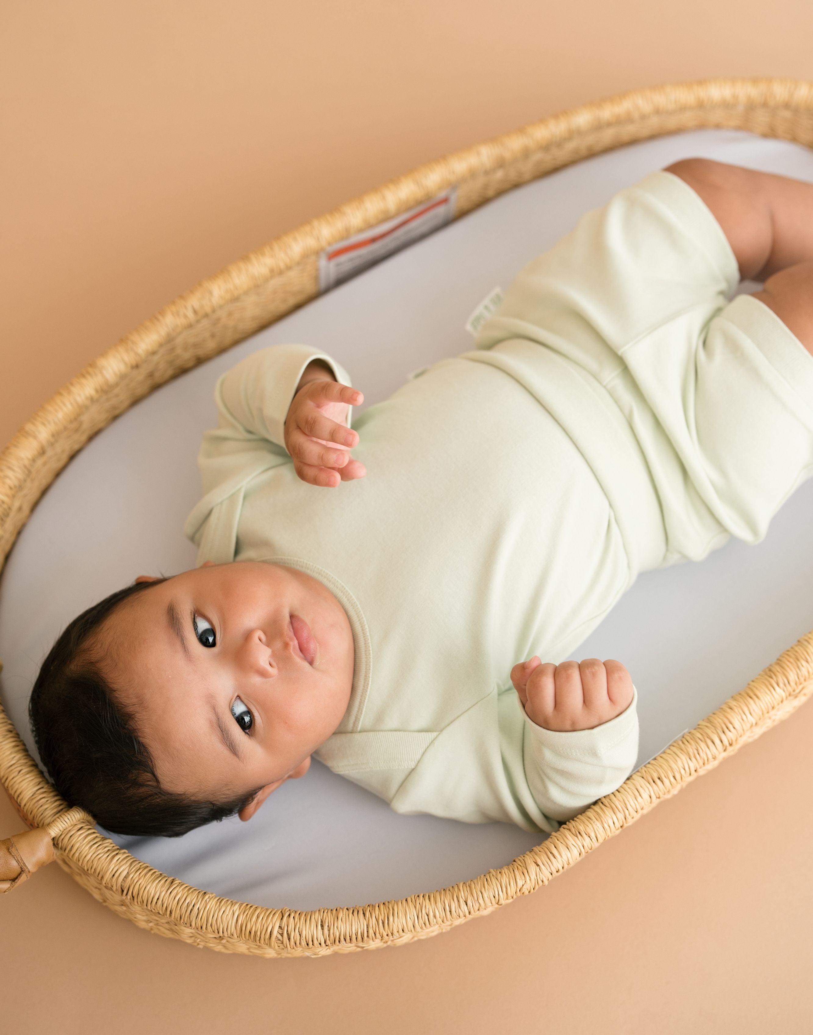 Baby wearing leafy green organic cotton long sleeve bodysuit and fold-over shorts