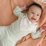 Smiling baby wearing leafy green organic cotton fold-over pants and matching long sleeve bodysuit