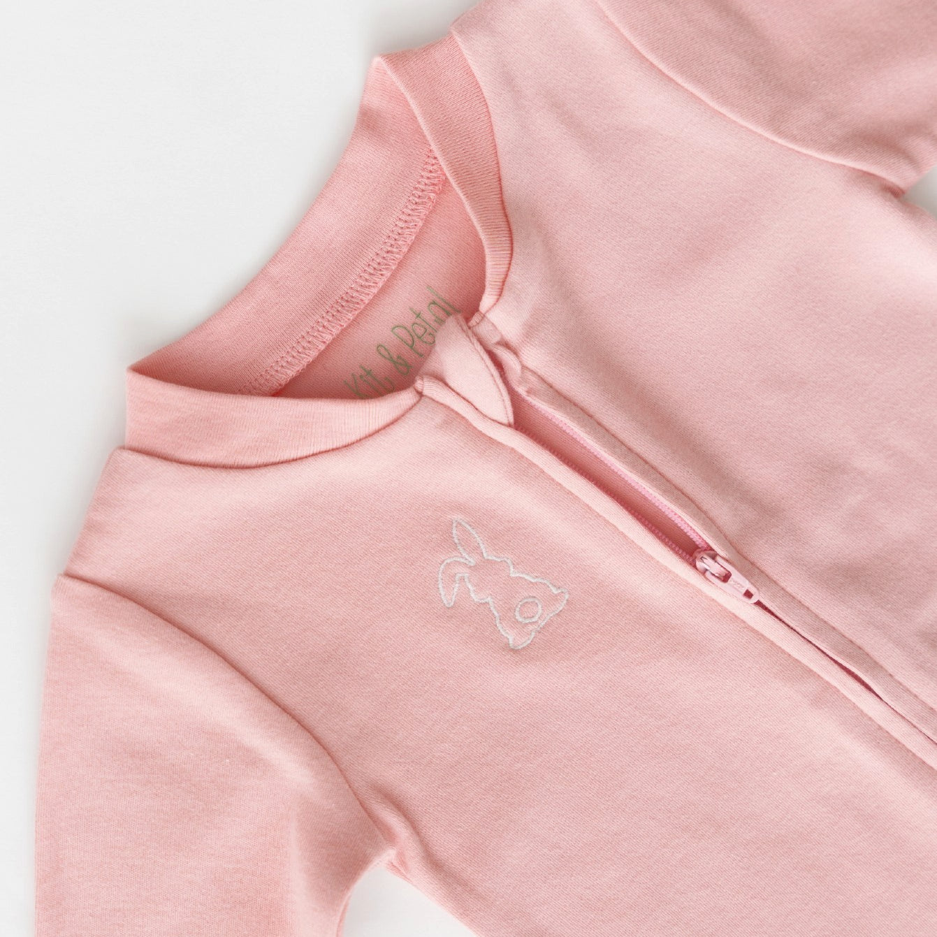 Long sleeve romper in pink with white bunny outline embroidery on the chest, zoomed in on open zipper