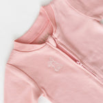 Long sleeve romper in pink with white bunny outline embroidery on the chest, zoomed in on open zipper