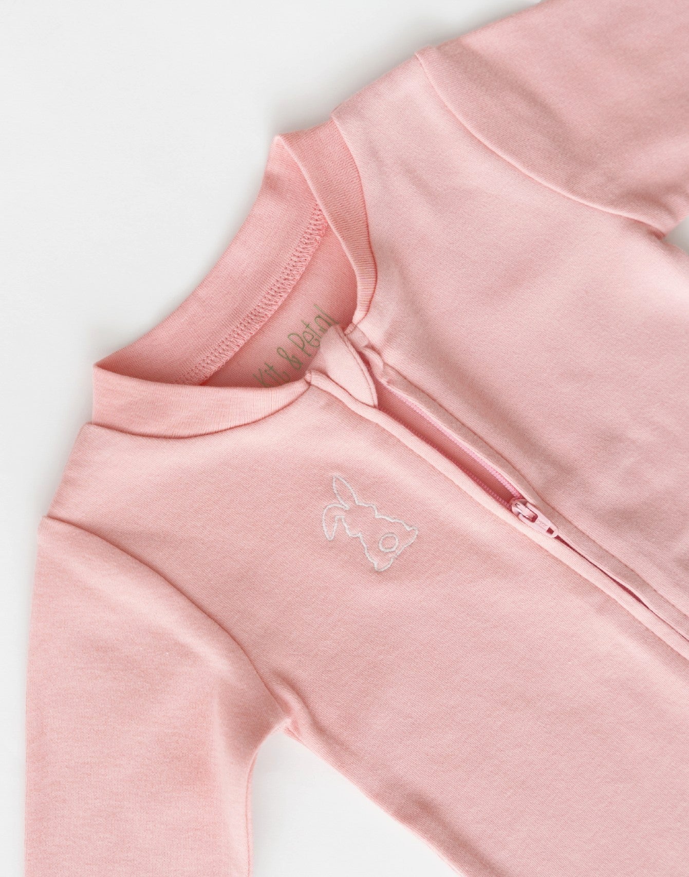 Long sleeve romper in pink with white bunny outline embroidery on the chest, zoomed in on open zipper