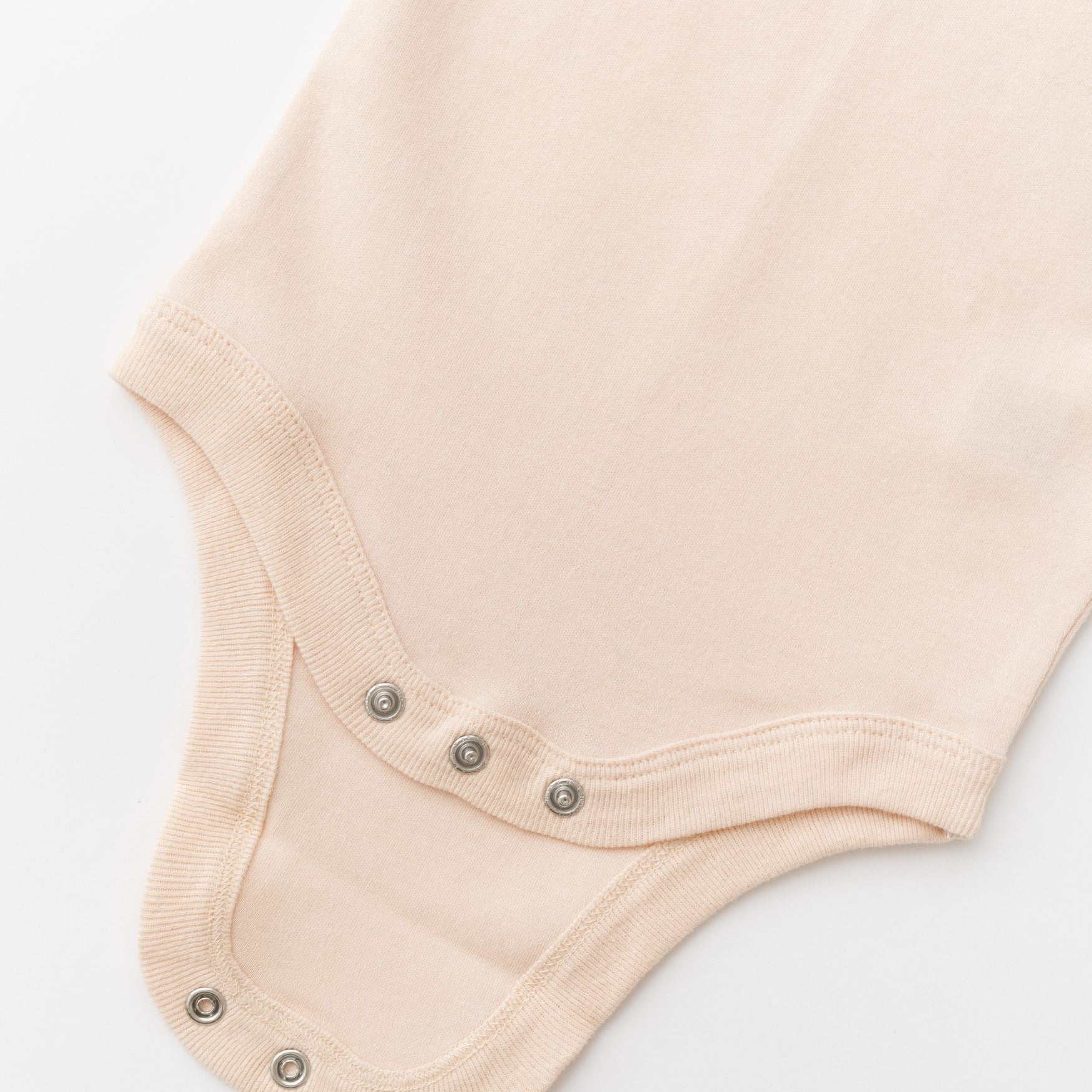 Close-up of snap buttons on rosy peach organic cotton baby long sleeve bodysuit