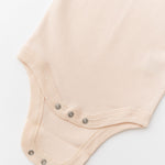 Close-up of snap buttons on rosy peach organic cotton baby short sleeve bodysuit