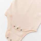 Close-up of snap buttons on rosy peach organic cotton baby short sleeve bodysuit