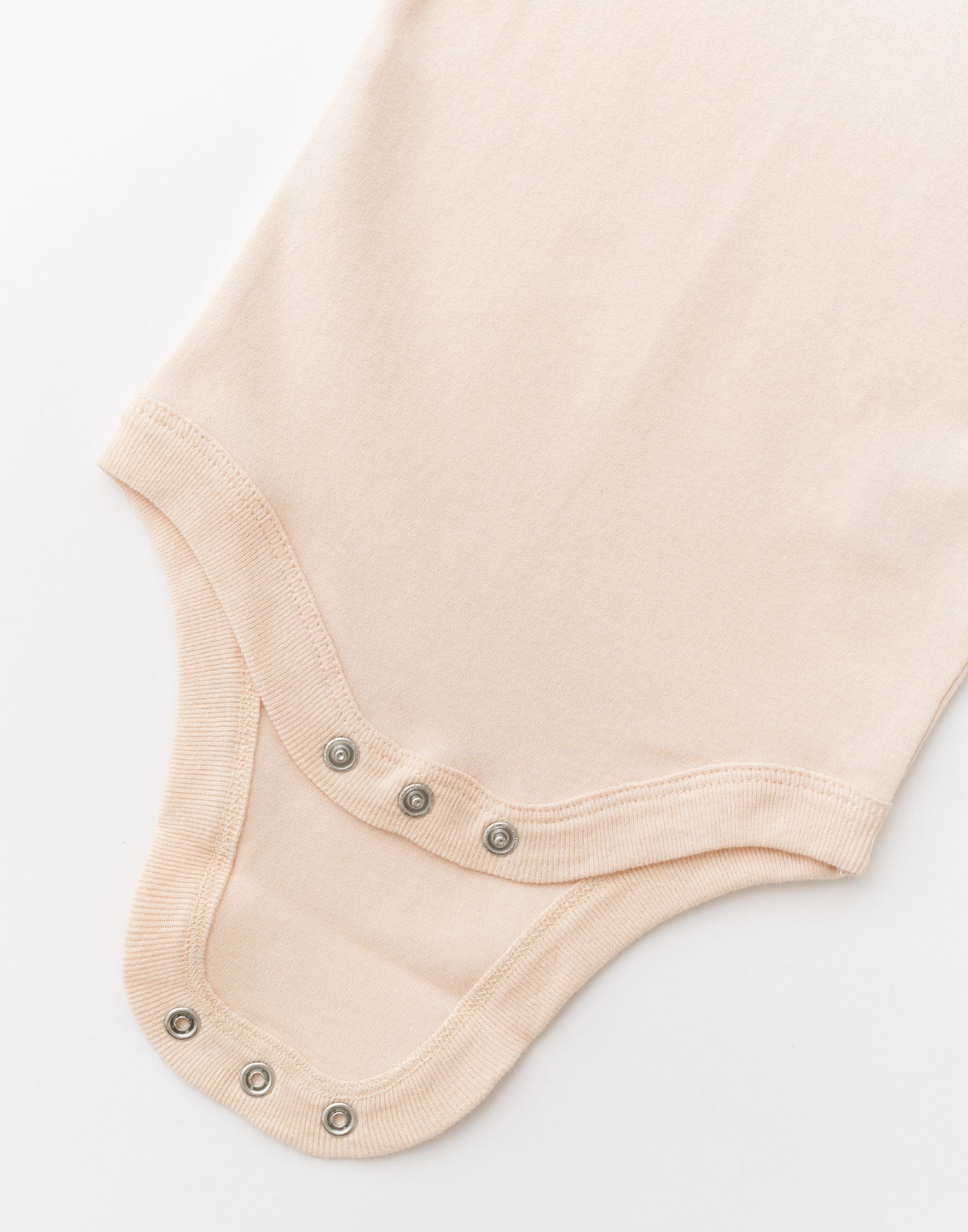 Close-up of snap buttons on rosy peach organic cotton baby short sleeve bodysuit