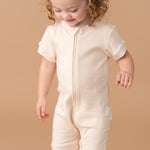 Toddler girl wearing a Rosy Peach organic cotton short sleeve romper.