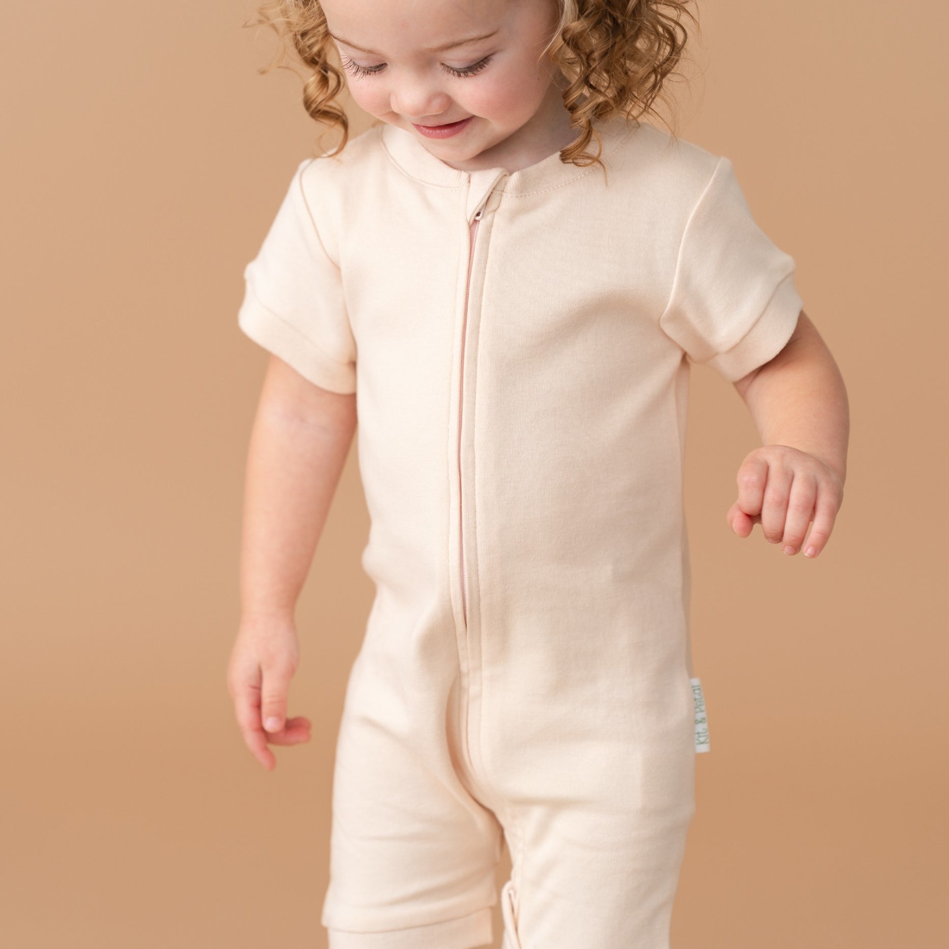Toddler girl wearing a Rosy Peach organic cotton short sleeve romper.