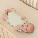 Baby lying in crib wearing leafy green organic cotton short sleeve bodysuit
