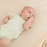Baby lying in crib wearing leafy green organic cotton short sleeve bodysuit