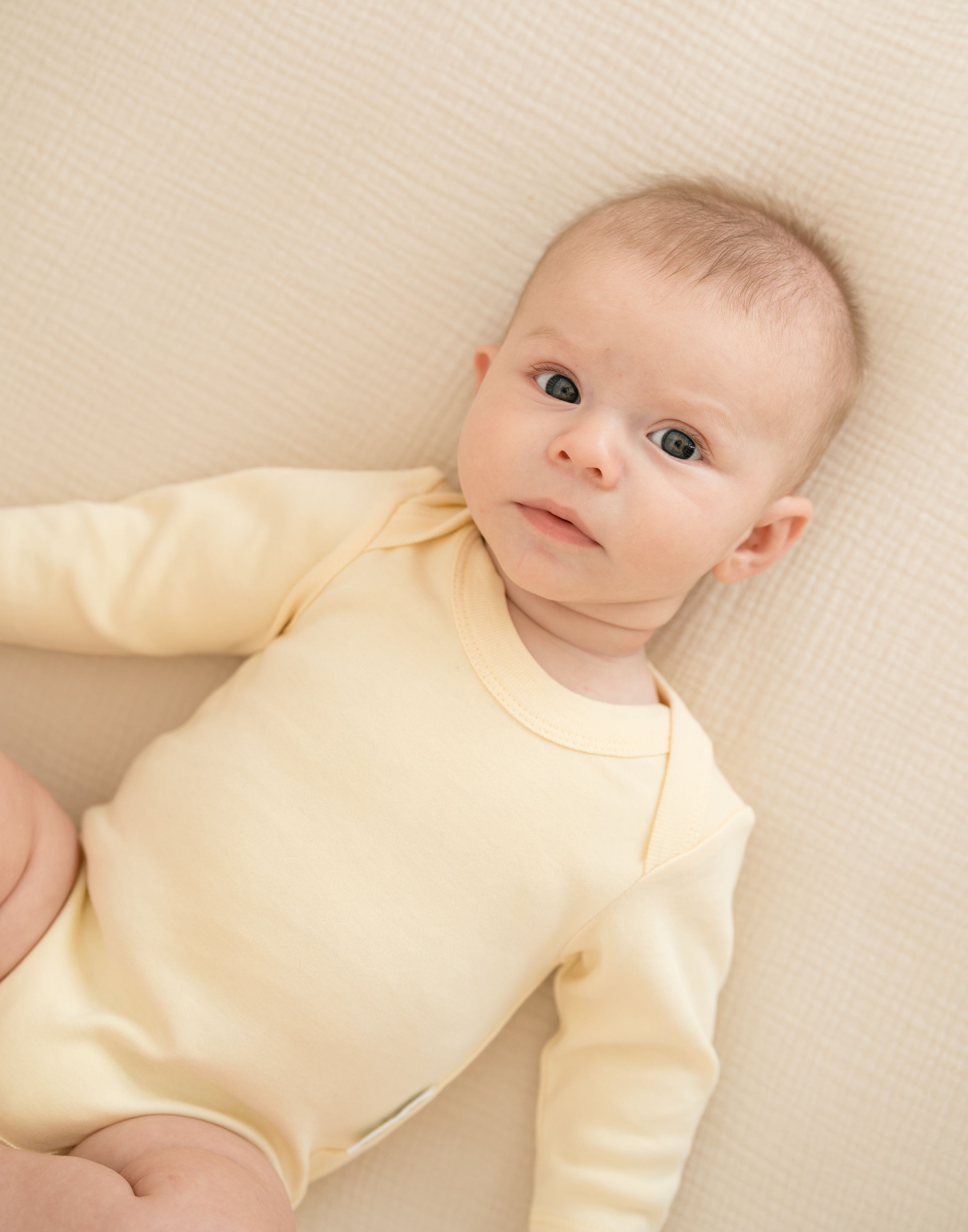 Baby wearing a Sunny Yellow organic cotton long sleeve bodysuit.
