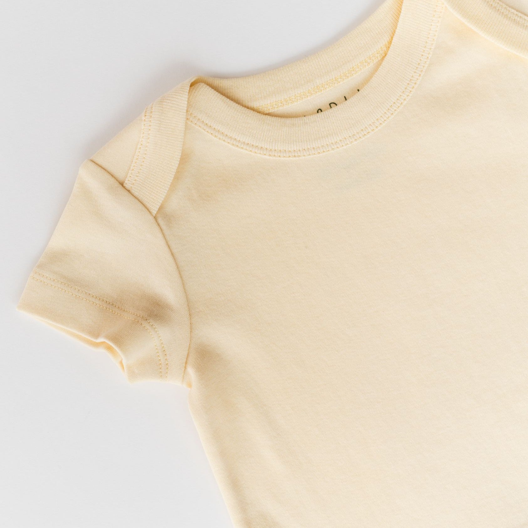 Close-up of Sunny Yellow organic cotton baby short sleeve shirt showing the envelope neckline.