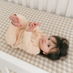 Baby lying in crib wearing rosy peach organic cotton long sleeve shirt and fold-over pants