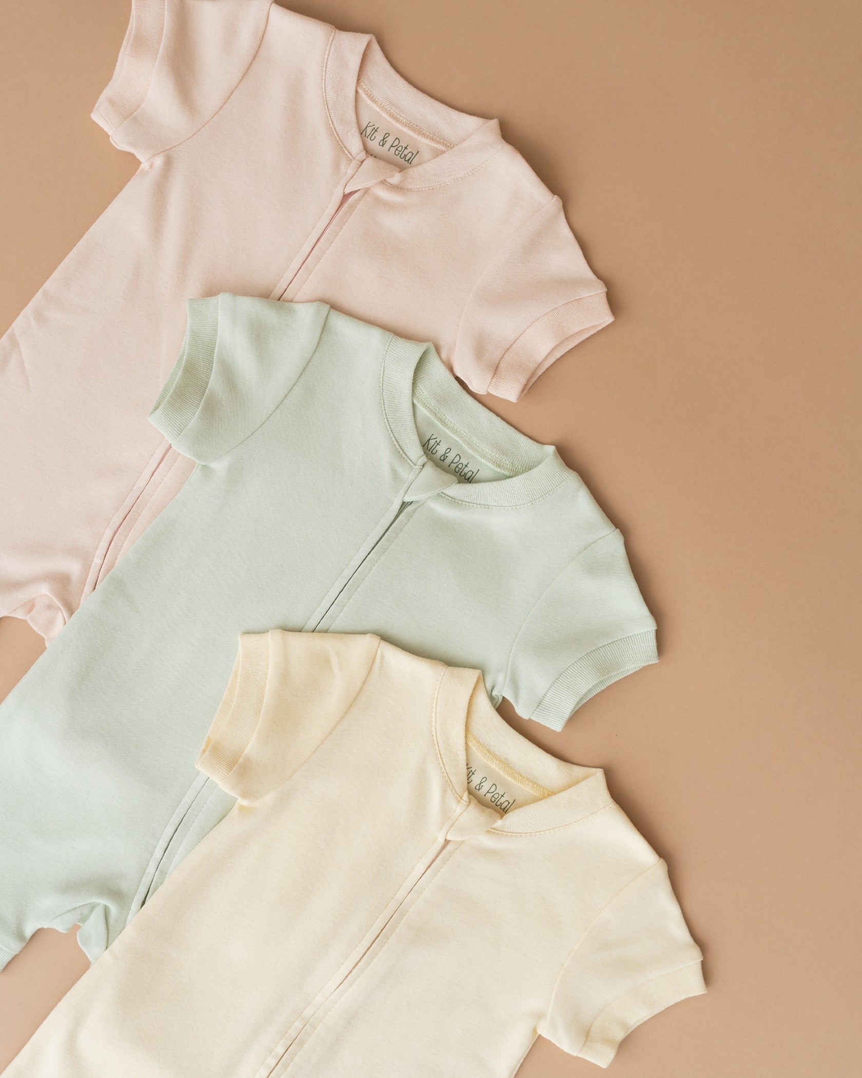 Three short sleeve rompers in all three colorways including peach, green and yellow
