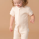 Toddler girl wearing a Rosy Peach organic cotton short sleeve romper.