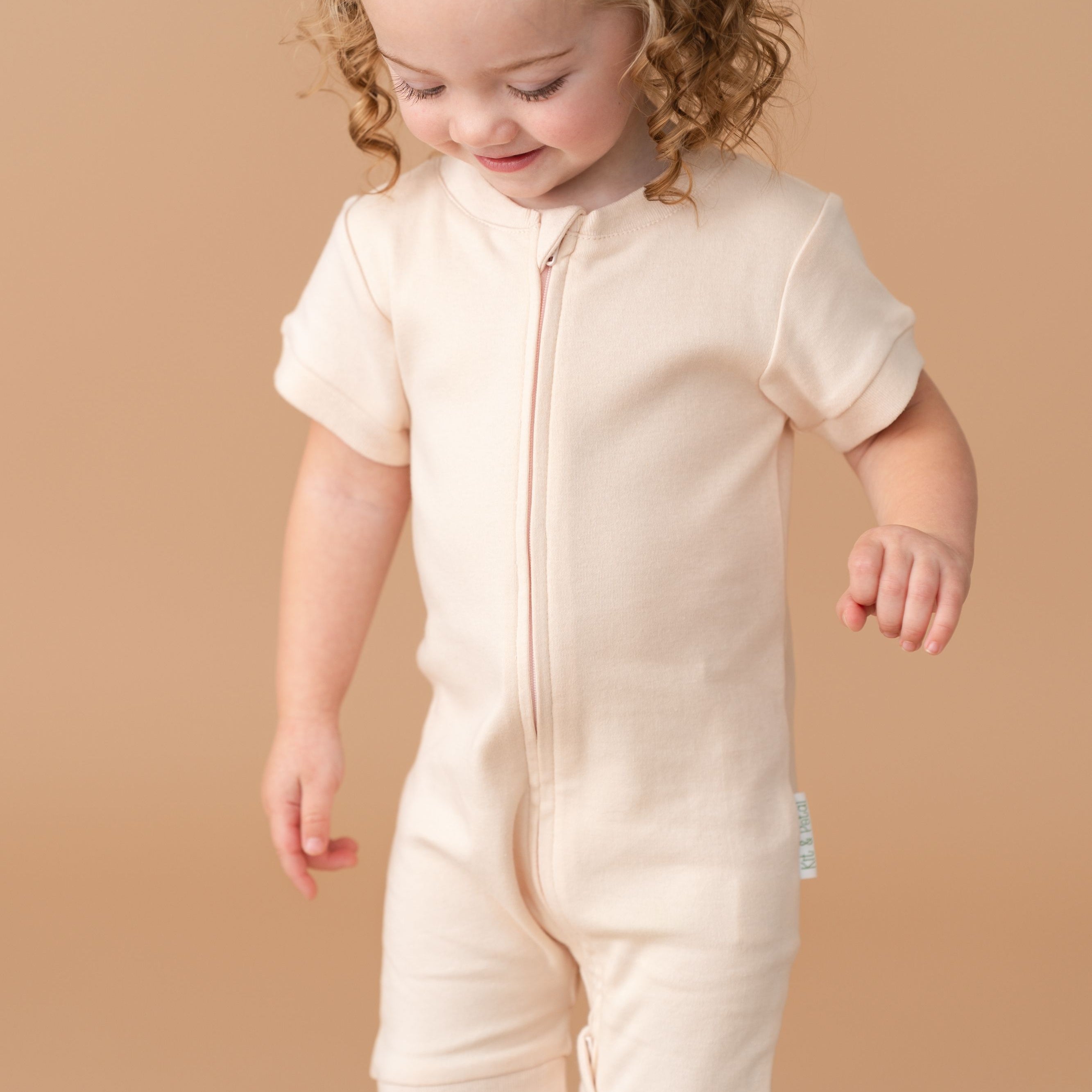 Toddler girl wearing a Rosy Peach organic cotton short sleeve romper.