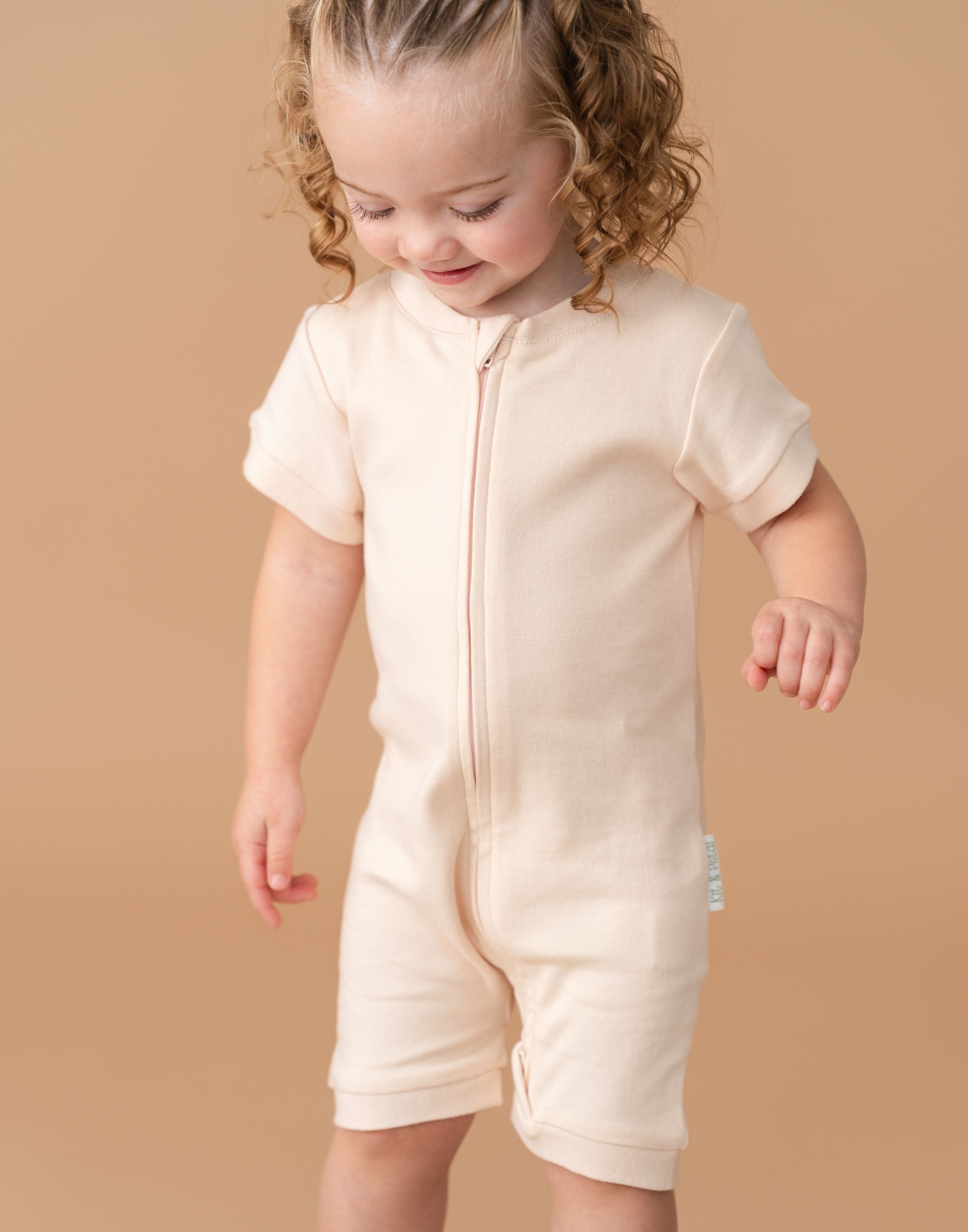 Toddler girl wearing a Rosy Peach organic cotton short sleeve romper.