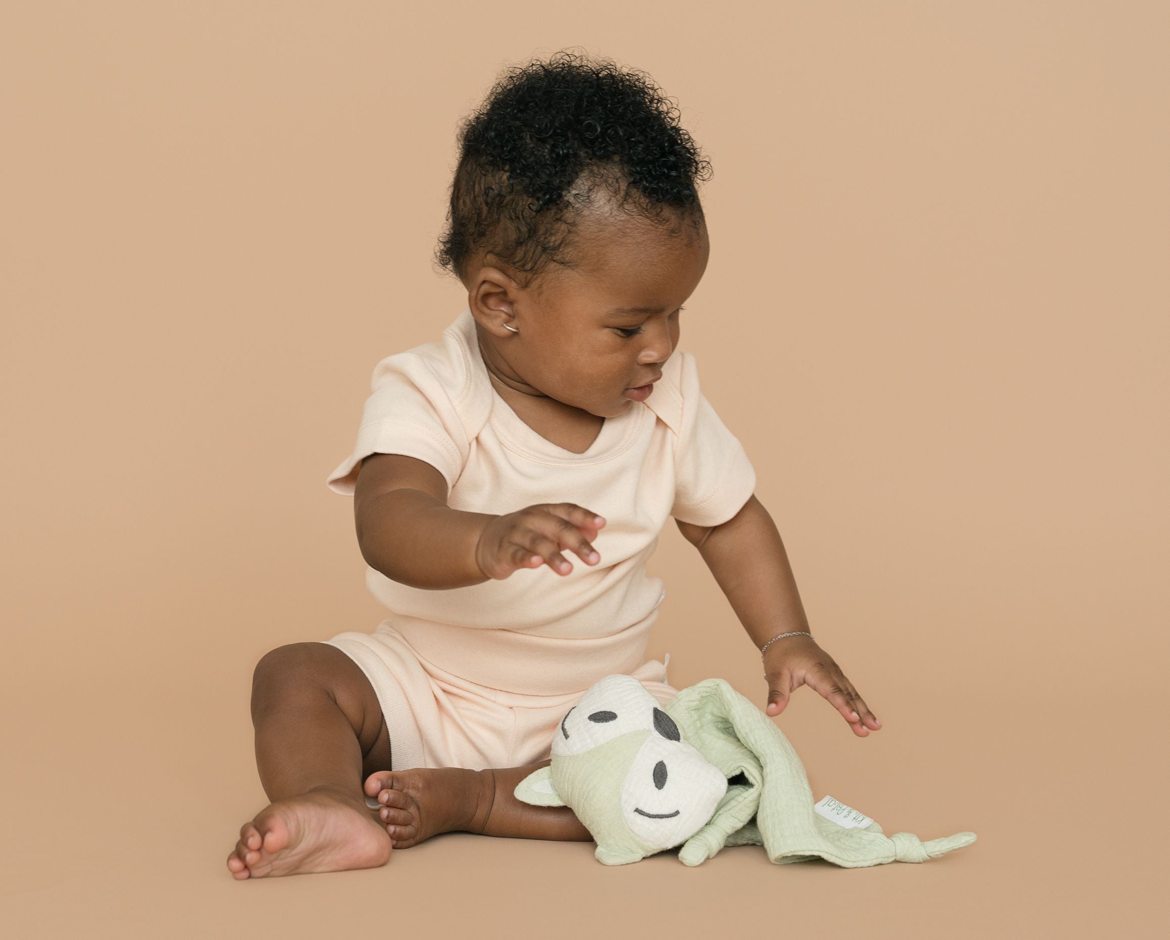 Baby wearing a Rosy Peach organic cotton short sleeve bodysuit and fold-over shorts, playing with a fox toy.