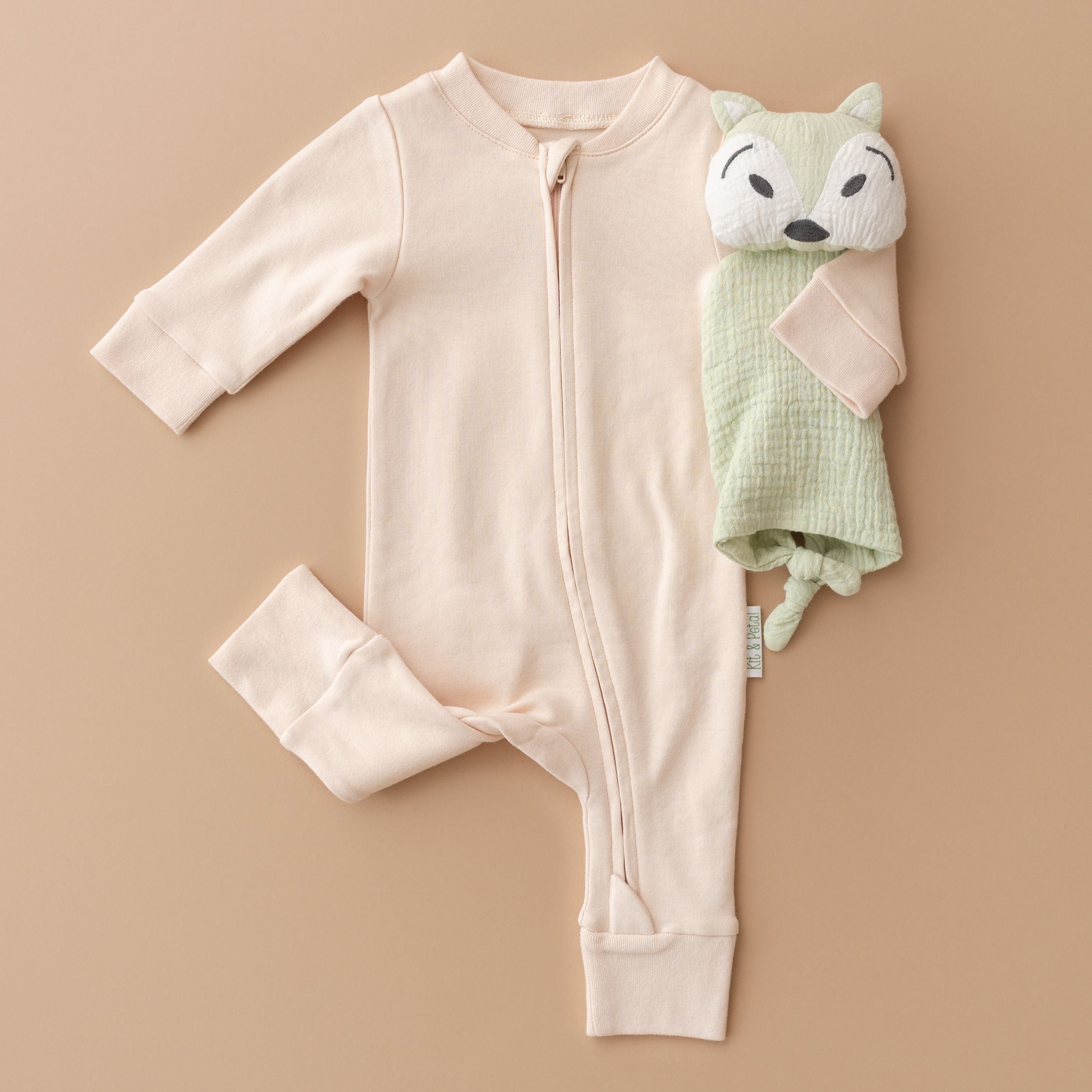 Flat lay of Kit & Petal Rosy Peach long sleeve romper paired with a fox toy.