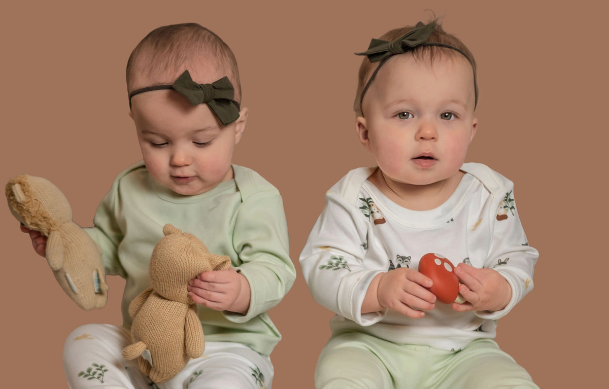 Twin babies wearing Kit & Petal long sleeve shirts and fold over pants in green and forest friends animal print