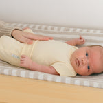 Baby laying in on a changing table wearing a Sunny Yellow organic cotton short sleeve bodysuit and fold-over shorts.
