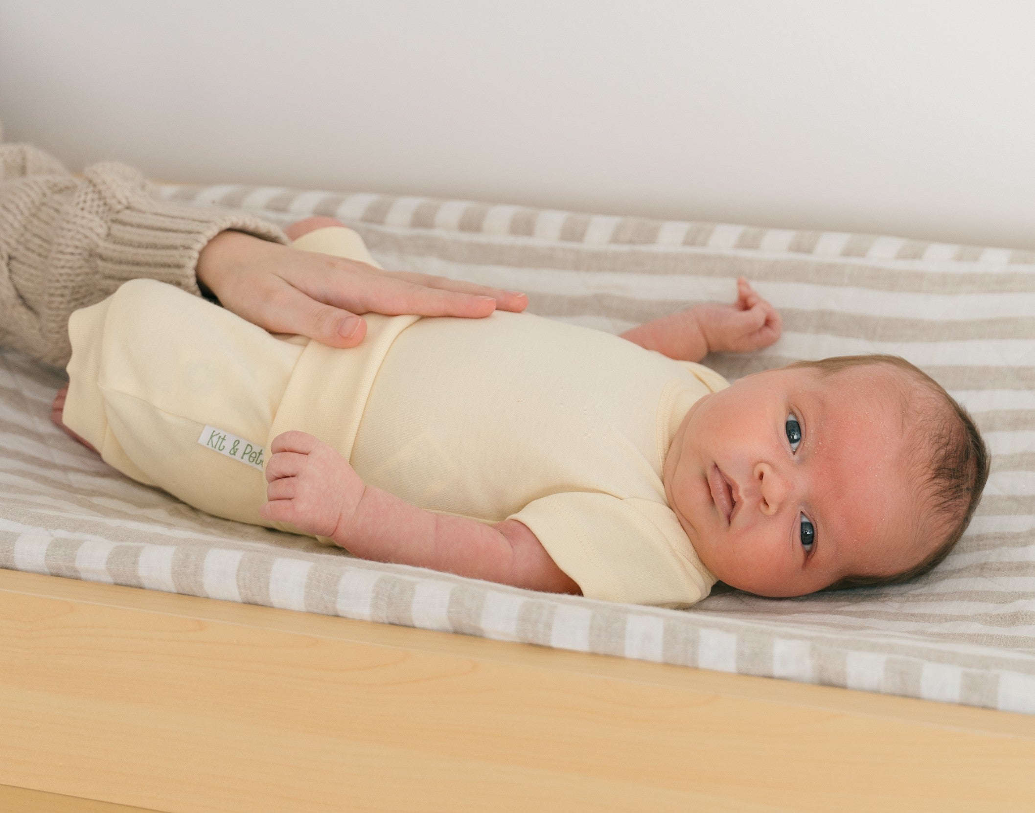 Baby laying in on a changing table wearing a Sunny Yellow organic cotton short sleeve bodysuit and fold-over shorts.